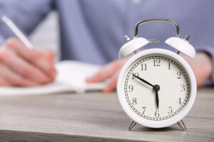 alarm clock in foreground, person writing in background