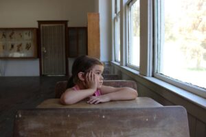 child gazing out of classroom window
