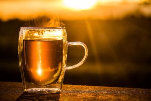 cup of black tea in a glass cup against a sunset